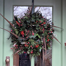 Load image into Gallery viewer, Decorative wreath with greenery and red berries hanging on a door.

